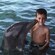 A dolphin appears to kiss a little boy on the cheek